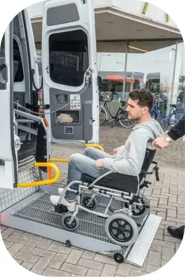 Man in wheelchair being assisted into an ambulette service van equipped with a wheelchair lift for safe, accessible transport