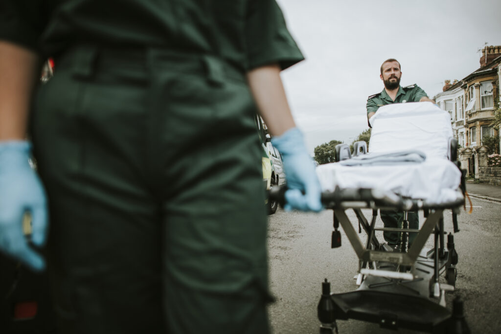 Paramedics transporting an empty stretcher along a street, prepared for patient care.